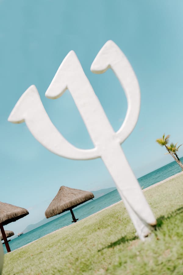 Sculpture blanche du trident Club Med sur ciel bleu, paillotes et mer en arrière-plan, Rio das Pedras