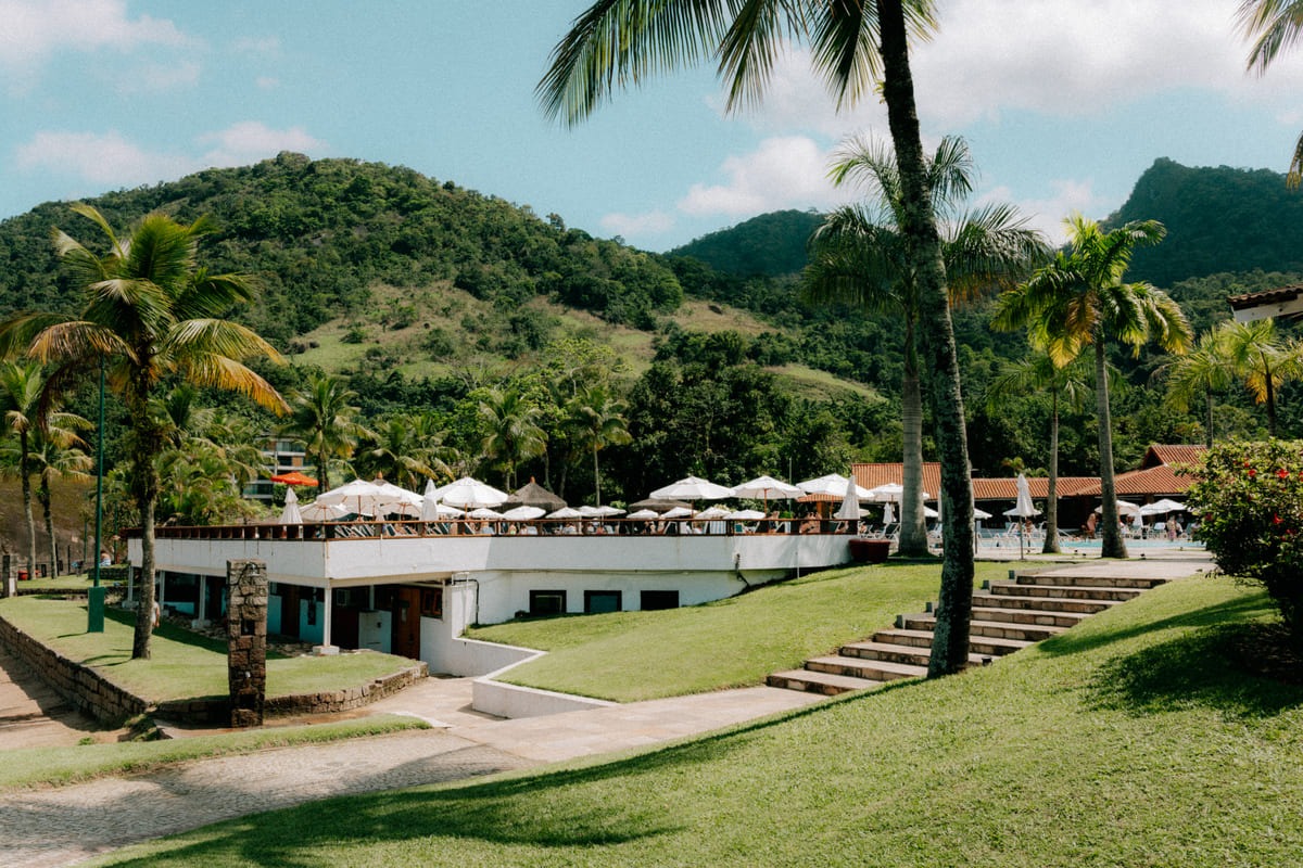 Vue d'ensemble du resort Club Med Rio das Pedras : pelouses, terrasses et parasols au pied des montagnes