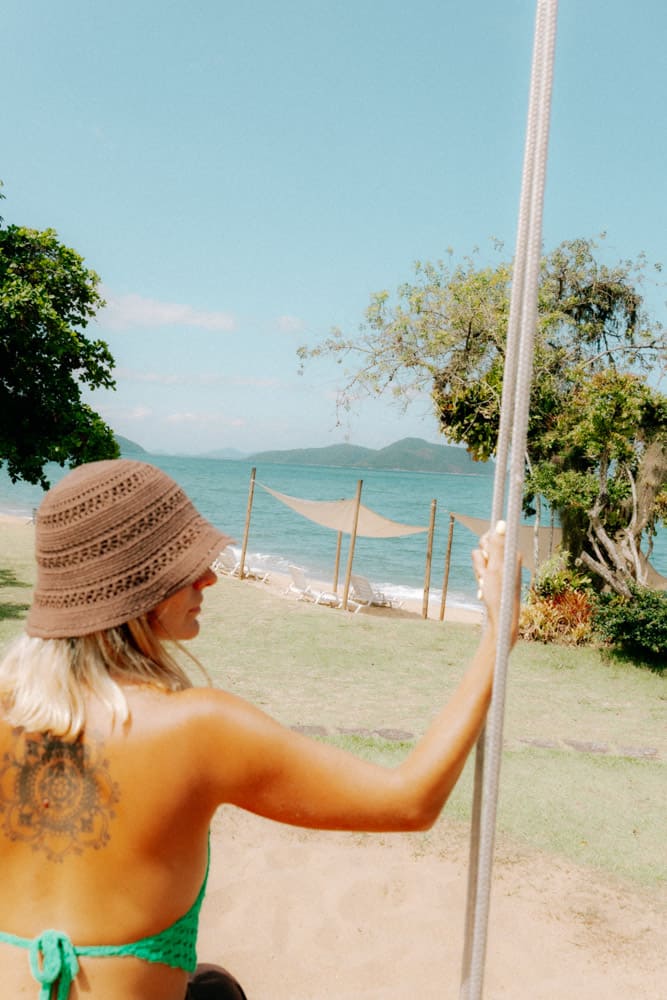 Femme en bikini vert et bob en crochet face à la plage, photographie lifestyle Club Med Rio das Pedras
