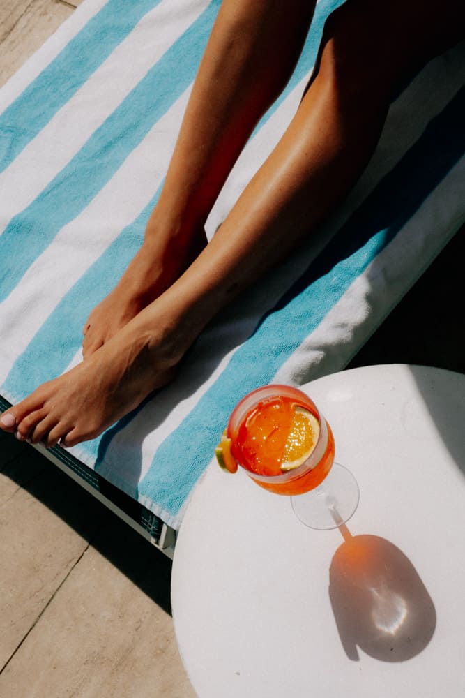 Vue plongeante sur un spritz, une table blanche et une serviette rayée au bord de la piscine, Club Med Rio das Pedras