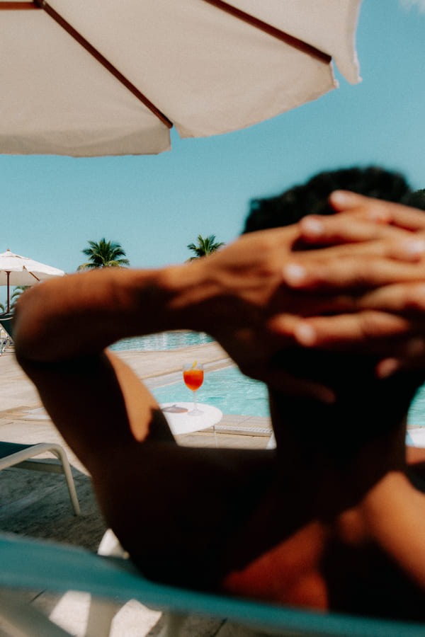 Homme détendu les mains derrière la tête sous un parasol, farniente au Club Med Rio das Pedras