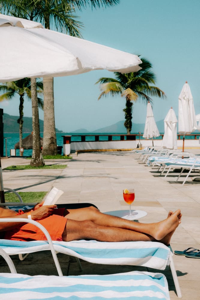 Vacancier allongé sur un transat au bord de la piscine, photographie lifestyle Club Med Rio das Pedras