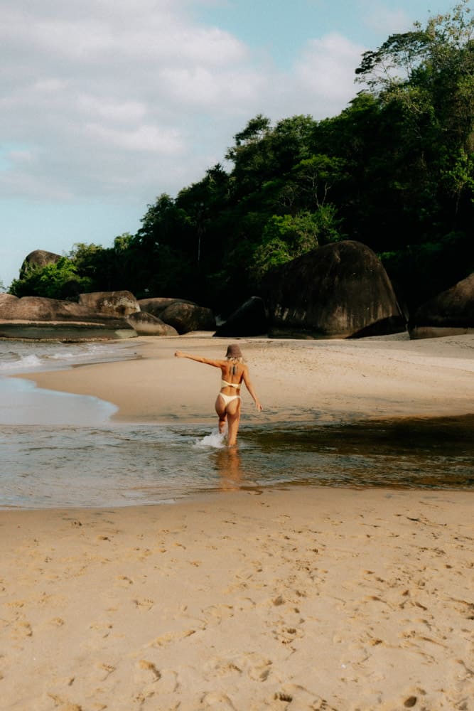 Femme marchant dans l'eau claire d'une crique de sable, photographie voyage au Club Med Rio das Pedras